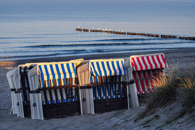 Hooded chairs on beach against sky