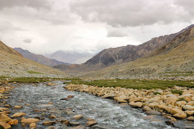 Scenic view of river by mountains against sky