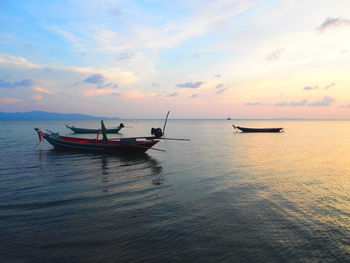 Boats in sea at sunset