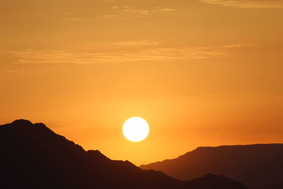 Scenic view of silhouette mountains against orange sky