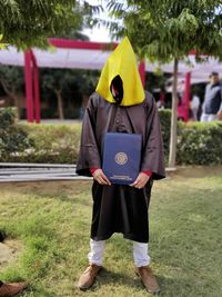 Anonymous wearing graduation dress with yellow hoodie