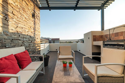 Terrace with outdoor furniture, stone on one wall, you can see the sky, barbecue area, steel pergola