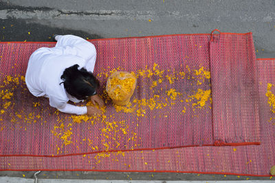 High angle view of woman collecting flower petals on mat