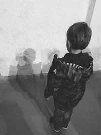 Rear view of boy standing against wall