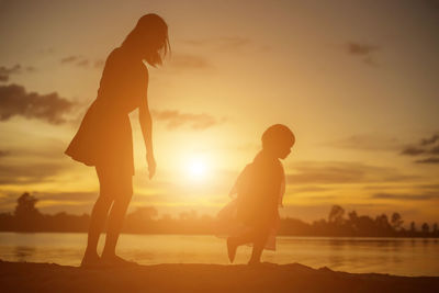 Silhouette couple on beach against sky during sunset