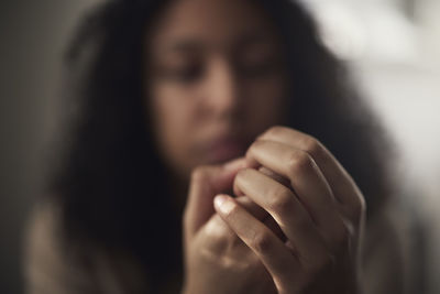 Pensive young woman picking at nails
