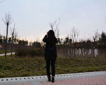 Rear view of woman standing against trees