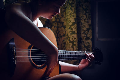 Side view of a woman playing guitar