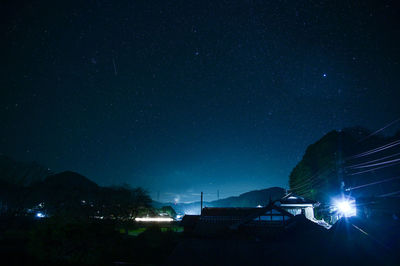 Illuminated street against sky at night