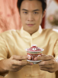 Portrait of man holding drink while at home during festival