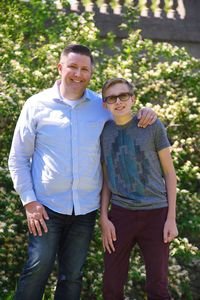 Portrait of father and son standing by plants at park