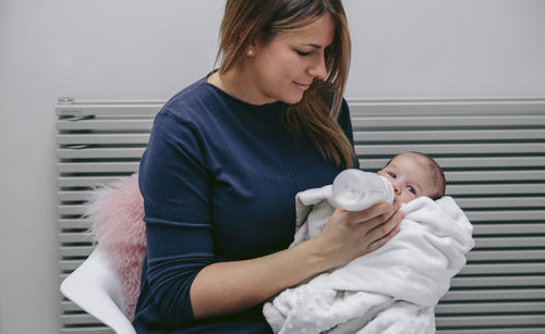 Mother feeding son with milk bottle