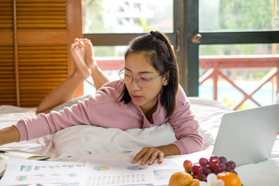 Young businesswoman using laptop while lying on bed