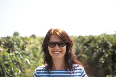 Portrait of young woman standing against clear sky