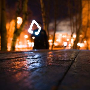 Close-up of illuminated light on wet street at night