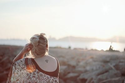 Rear view of woman standing at beach against clear sky