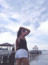 Young woman standing on pier against sky