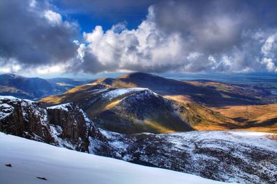 Scenic view of snow covered mountains against cloudy sky