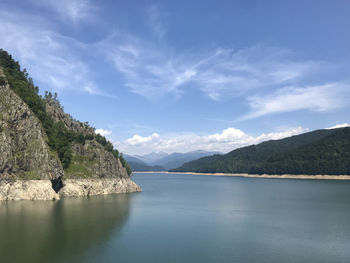 Scenic view of sea and mountains against blue sky