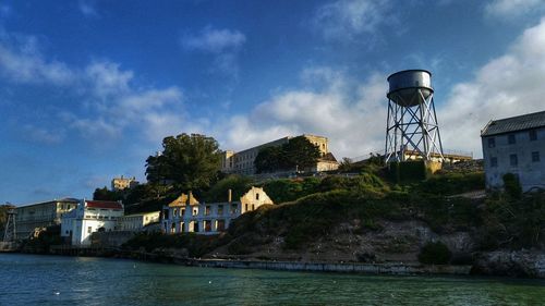 River by buildings and water tower and buildings against cloudy sky