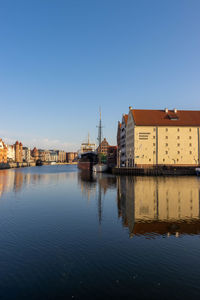 Buildings by river against sky in city