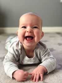 Close-up of happy baby boy lying on carpet at home