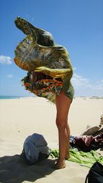 Midsection of woman on beach against sky