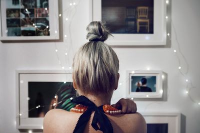 Rear view of woman with hair bun with picture frames at home
