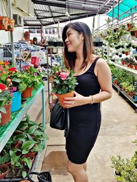 Woman holding potted plant while standing at market stall