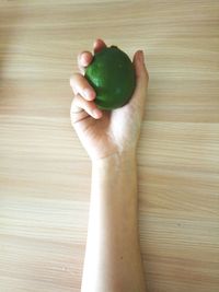 Cropped image of hand holding lemon on wooden table