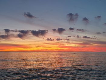 Scenic view of sea against dramatic sky during sunset