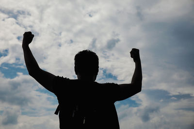 Rear view of silhouette man using smart phone against sky