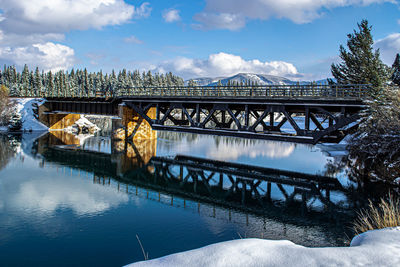 Bridge over river against sky during winter