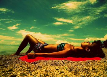 Low section of woman relaxing on sand