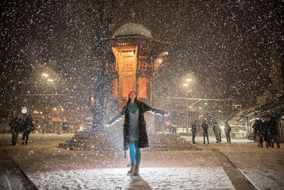 Woman standing on road against sky during snowfall