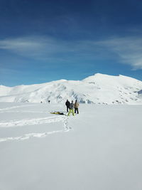 People on snowcapped mountain against sky