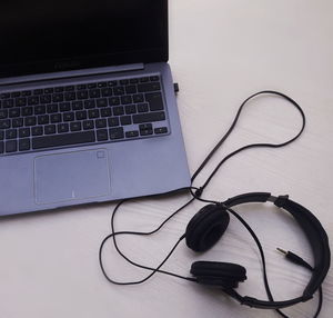 High angle view of headphones by laptop on table