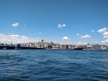 Sea by buildings against blue sky