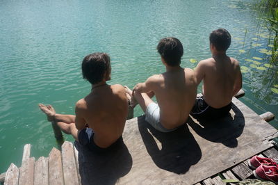 Rear view of two men sitting on water