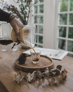 Man pouring coffee in glass on table