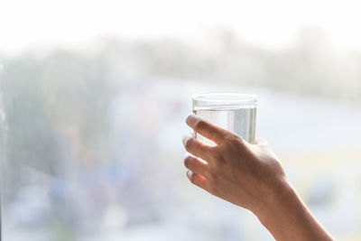 Close-up of hand holding water against sky