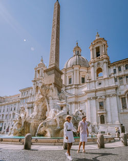 Couple outside historic building against sky in city