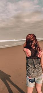 Rear view of woman on beach against sky