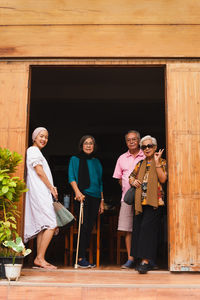 Happy serion people with adult daughter standing in the door frame or the house.