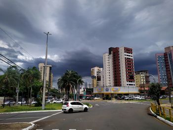 Cars on road by buildings against sky