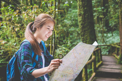 Young woman smiling while sitting on land in forest