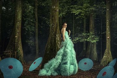 Woman standing by tree trunk in forest