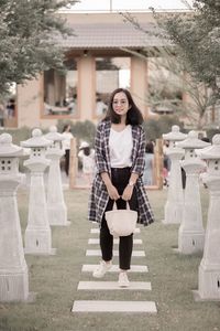 Portrait of young woman standing against trees