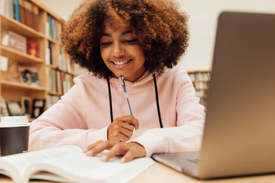 Teenage girl with laptop studying in library