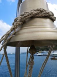 Close-up of rope tied on wooden post in sea against sky